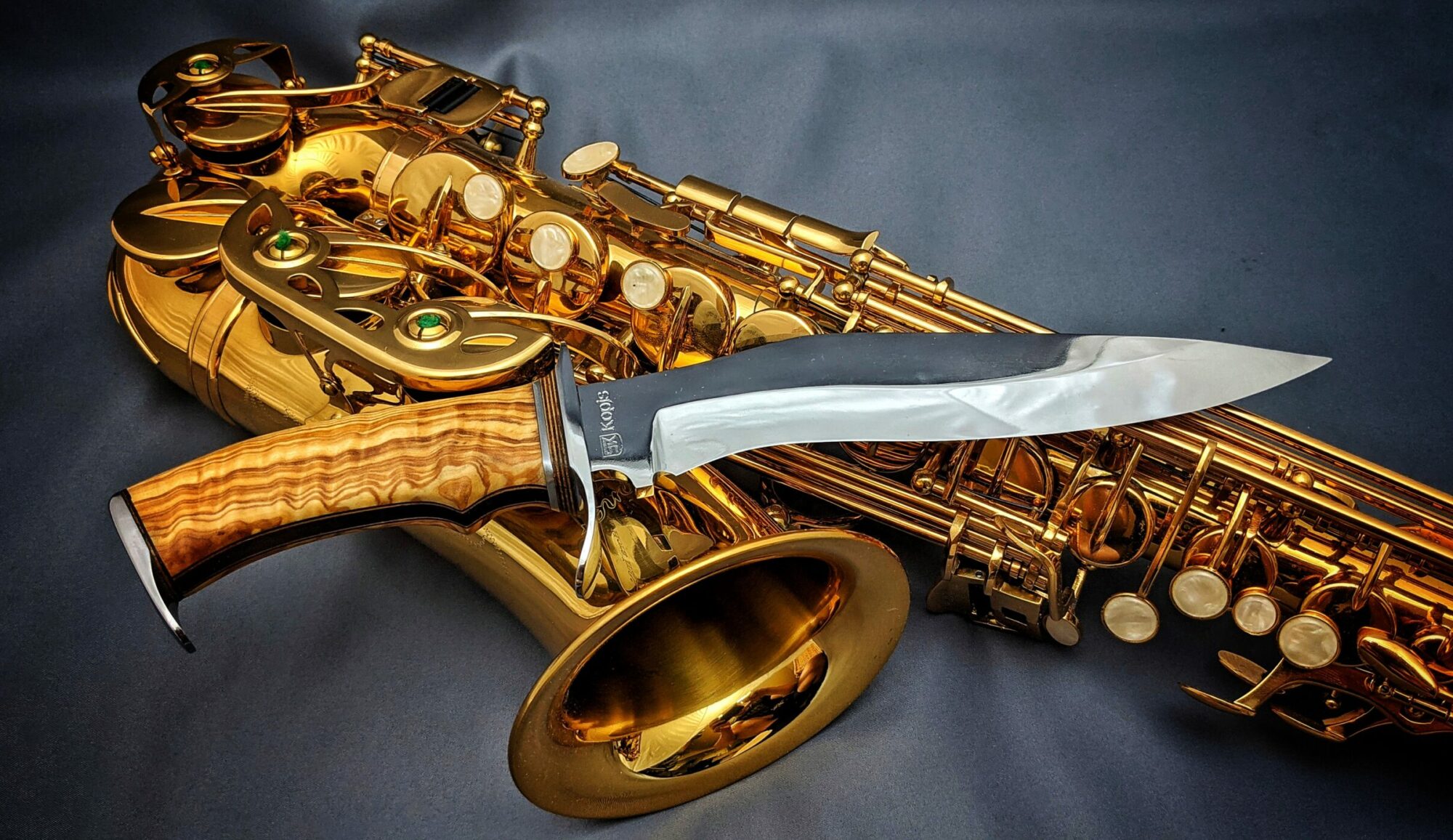 Beauty shot of a Kopis style handmade knife in front of Saxophone full width for cover